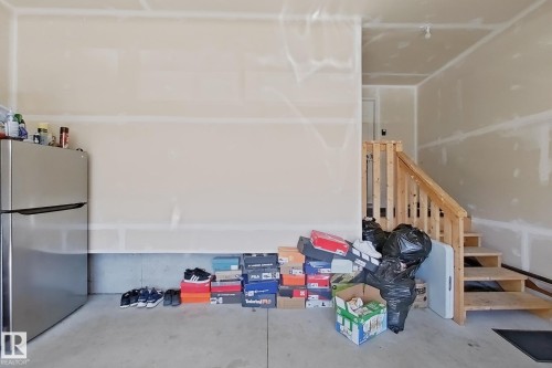 Garage interior featuring an unfinished wall, concrete flooring, and a wooden staircase - 415 42 Street, Edmonton, AB 