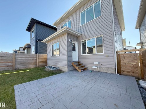 Exterior featuring light gray siding, multiple windows, and a stamped concrete patio - 415 42 Street, Edmonton, AB 