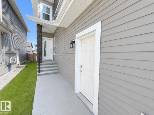 Exterior entry featuring light gray horizontal siding and a white paneled door - 415 42 Street, Edmonton, AB 
