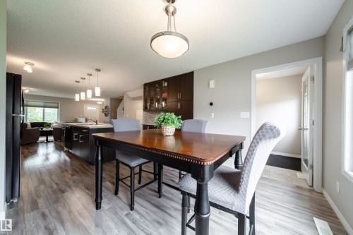 Open-concept living space featuring wood-finish flooring, recessed lighting, a kitchen island with pendant lighting, and dark wood cabinetry - 3211 Cherry Crescent, Edmonton, AB 