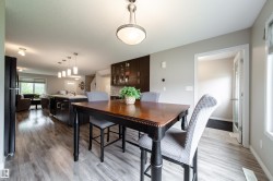 Open-concept living space featuring wood-finish flooring, recessed lighting, a kitchen island with pendant lighting, and dark wood cabinetry - 