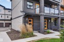 Modern exterior featuring horizontal siding in contrasting tones, brick accents, and vibrant orange entry doors - 1203 163 Street Sw, Edmonton, AB 