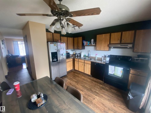 Kitchen featuring wood-finish cabinetry, dark countertops, and wood-finish flooring - 5713 44A Street, Vegreville, AB 