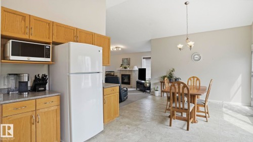 Kitchen and dining area featuring wood cabinetry, a built-in microwave, and tile flooring - 6105 52 Avenue, Beaumont, AB 
