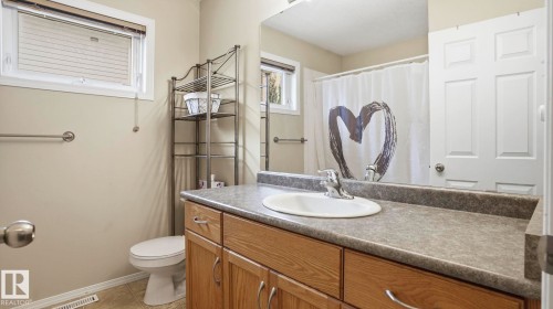 Bathroom vanity featuring a built-in sink, laminate countertop, and wood-finish cabinetry with silver-tone hardware - 6105 52 Avenue, Beaumont, AB 