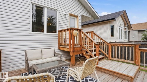 Multi-level wood deck featuring built-in railings, steps, and white vinyl siding on the exterior - 6105 52 Avenue, Beaumont, AB 