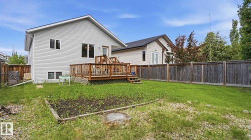 Expansive backyard featuring a wood deck, perimeter wood fencing, and a raised garden bed - 6105 52 Avenue, Beaumont, AB 