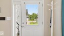 White paneled entry door with grid-patterned glass insert and brushed nickel hardware, accompanied by a full-length sidelight with integrated grids - 6105 52 Avenue, Beaumont, AB 