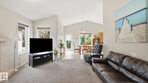 Open-concept living space featuring vaulted ceilings, light-colored walls, and gray carpeting - 6105 52 Avenue, Beaumont, AB 