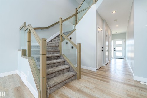 Modern staircase with glass panel railing and light wood-finish posts - 17320 9 Avenue, Edmonton, AB 