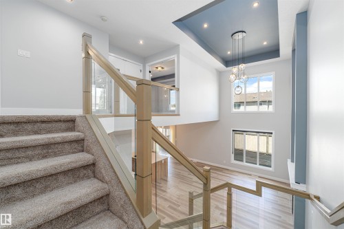 Expansive foyer with a two-story ceiling, contemporary chandelier, and large windows - 17320 9 Avenue, Edmonton, AB 