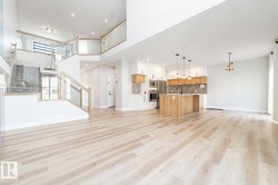 Spacious open-concept living area featuring light wood-finish flooring - 