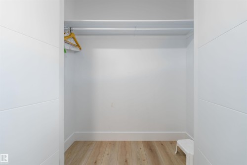 Spacious closet featuring light wood-finish flooring, white baseboards, and a white hanging rod with shelf above - 17320 9 Avenue, Edmonton, AB 