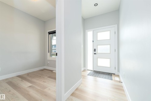 Modern entryway featuring a white door with three frosted glass panels and a sidelight - 17320 9 Avenue, Edmonton, AB 