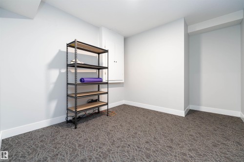 Carpeted room featuring a white baseboard, a built-in wall cabinet, and a structural beam - 17320 9 Avenue, Edmonton, AB 