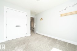 Room featuring light gray carpeting, white walls, and modern white doors with black hardware - 