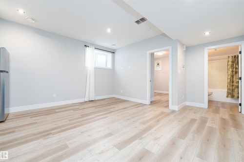 Light wood-finish flooring throughout a spacious room with recessed lighting - 17320 9 Avenue, Edmonton, AB 