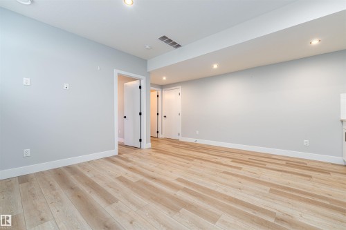 Spacious open room featuring light wood-finish flooring, recessed lighting, white baseboards, and light gray walls - 17320 9 Avenue, Edmonton, AB 