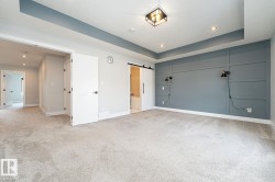 Spacious room featuring a decorative accent wall, tray ceiling, recessed lighting, and soft carpet flooring - 