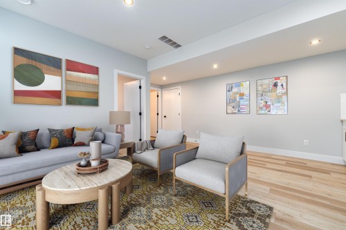 Expansive living area with light wood-finish flooring and recessed lighting - 17320 9 Avenue, Edmonton, AB 