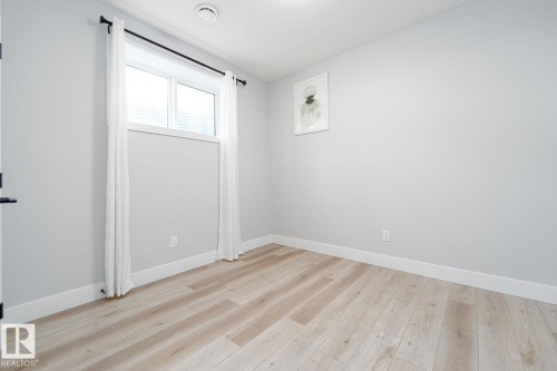 Modern kitchen area featuring white cabinetry, stainless steel appliances, and a light wood-finish flooring - Edmonton, AB 