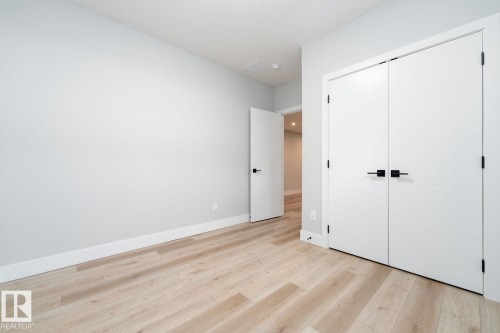 Spacious room featuring light wood-finish flooring, recessed lighting, a window with natural light, and access to a full bathroom with a shower-over-tub combination - Edmonton, AB 