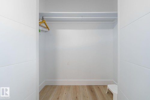 Spacious room featuring light-toned wood-finish flooring, recessed lighting, and crisp white trim - Edmonton, AB 