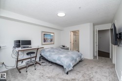 Carpeted room featuring a ceiling-mounted light fixture, white walls, and a doorway revealing a bathroom with a glass shower enclosure - 