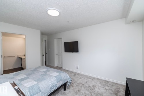 Carpeted room with a circular ceiling light fixture and white walls - 111 182 Haddow Close, Edmonton, AB 