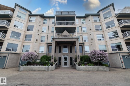 Multi-level residential building featuring a textured facade, numerous balconies with white railings, and an integrated main entrance with a portico - 111 182 Haddow Close, Edmonton, AB 