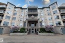 Multi-level residential building featuring a textured facade, numerous balconies with white railings, and an integrated main entrance with a portico - 111 182 Haddow Close, Edmonton, AB 