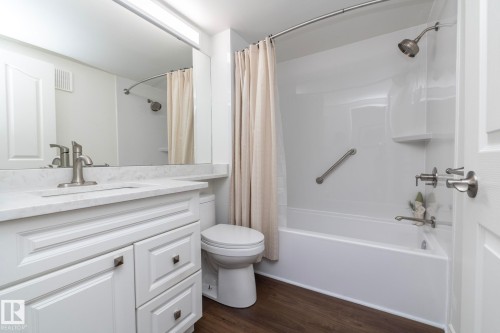 Bathroom featuring a white vanity with a light-toned countertop, brushed nickel faucet, large mirror, and overhead lighting - 111 182 Haddow Close, Edmonton, AB 