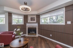 Living area featuring a gas fireplace with a white mantel, wood-finish flooring, and slatted accent walls - 