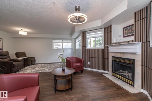 Living area featuring a fireplace with a white mantel and light-toned tile surround - 111 182 Haddow Close, Edmonton, AB 