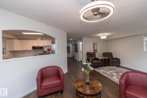 Spacious living area featuring wood-finish flooring, white walls, and a contemporary ceiling fan with integrated lighting - 111 182 Haddow Close, Edmonton, AB 