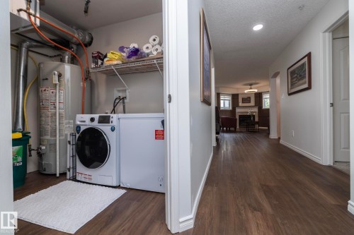 Dedicated laundry closet featuring a front-load washing machine, wire shelving, and wood-finish flooring - 111 182 Haddow Close, Edmonton, AB 