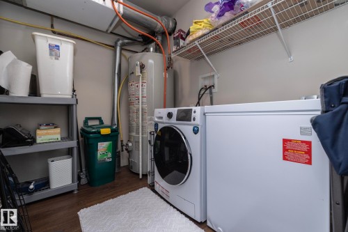 Dedicated utility area featuring a water heater, wood-finish flooring, and overhead wire shelving - 111 182 Haddow Close, Edmonton, AB 