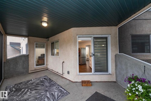 Covered patio featuring a concrete floor, textured stucco walls, and an exterior ceiling light fixture - 111 182 Haddow Close, Edmonton, AB 