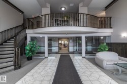 Multi-level lobby featuring a grand staircase with dark wood-finish railings, an upper-level balcony, and a tiled entryway - 