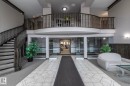 Multi-level lobby featuring a grand staircase with dark wood-finish railings, an upper-level balcony, and a tiled entryway - 111 182 Haddow Close, Edmonton, AB 