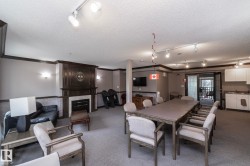 Spacious common area featuring a dark wood mantel fireplace with a light-colored surround, track lighting, wall sconces, and carpet flooring - 