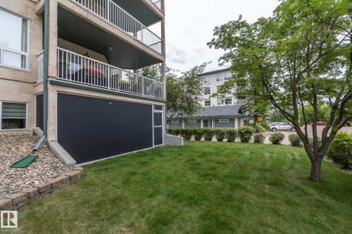 Ground-level exterior featuring a manicured lawn, a retaining wall with stone pavers, and a gravel bed - 111 182 Haddow Close, Edmonton, AB 