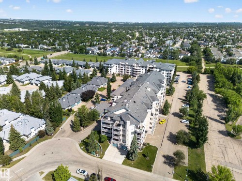 Aerial perspective showcasing the multi-story residential building with light-colored siding and numerous balconies - 111 182 Haddow Close, Edmonton, AB 