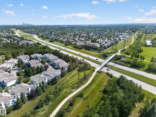 Aerial perspective showcasing a residential community with multi-lane roads, green spaces, and a pedestrian overpass - 111 182 Haddow Close, Edmonton, AB 
