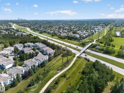 Aerial perspective showcasing a residential community with multi-lane roads, green spaces, and a pedestrian overpass - 