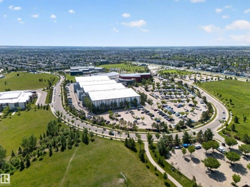 Expansive commercial property featuring multiple large buildings with light-colored roofing, extensive paved parking areas, and surrounding green spaces - 111 182 Haddow Close, Edmonton, AB 