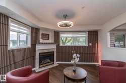 Living area featuring a gas fireplace with a stone surround and mantle, wood-finish flooring, and slatted accent walls - 