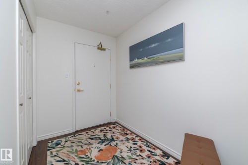 Entryway featuring a white door with brass hardware, wood-finish flooring, and a bi-fold closet door - 111 182 Haddow Close, Edmonton, AB 