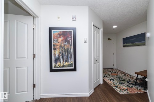 Entryway featuring wood-finish flooring, white paneled doors, and white baseboard trim - 111 182 Haddow Close, Edmonton, AB 