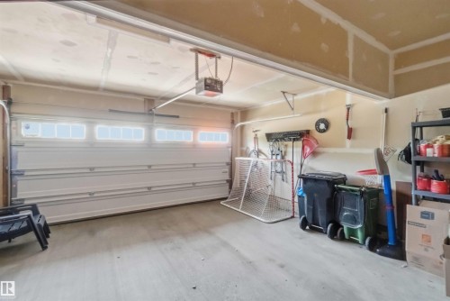 Garage featuring a white paneled door with transom windows, a concrete floor, and unpainted drywall - 20013 131 Avenue, Edmonton, AB 